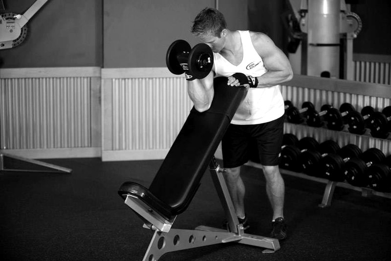 Standing One-Arm Dumbbell Curl Over Incline Bench — end position demonstration photo