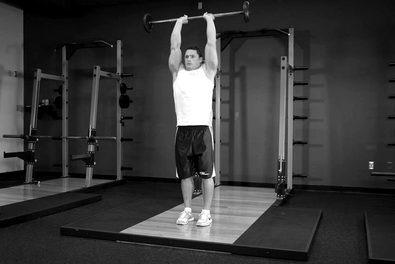 Standing Overhead Barbell Triceps Extension — end position demonstration photo